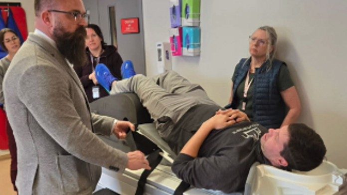 Live demo: presenter fitting KyphoLift straps with a person on the MRI table